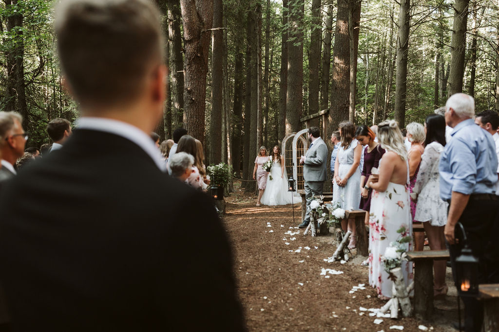 bride walks down isle forest wedding ontario